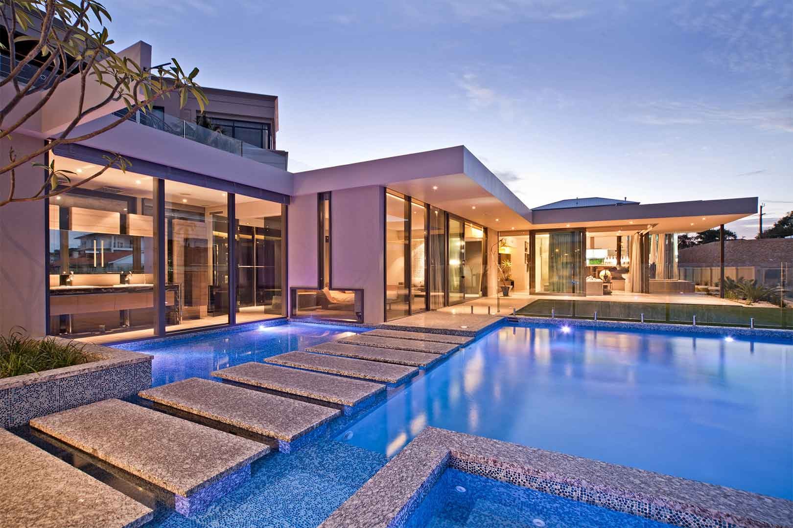 Modern Perth home with a lit pool at dusk